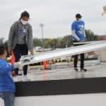 Paul Leaman, head of school, picks up panel from Rahel Lema '21 at the solar barn raising