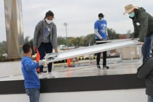 Paul Leaman, head of school, picks up panel from Rahel Lema '21 at the solar barn raising