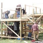 "Fleet of helpers" constructing multi-level, multi-tier stage to accommodate the required 10-foot distancing. 