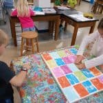 Title: The Colorful GhostsSize: 24”x18”Media: acrylic paintDescription: 1st grade artists used printmaking to create a colorful quilt-like composition. Each student rolled paint onto a rectangular piece of foam and stamped the shape onto the wooden panel. After designing a printmaking block with foam shapes, they rolled paint onto it and stamped it directly over their solid block of color. Students repeated this process with a partner to create a second print. These student pairs practiced sharing their ideas for design and color choices. The last printed block was created by the entire class. As the final step in their creative process, the class brainstormed title ideas for their piece then voted for their favorite.