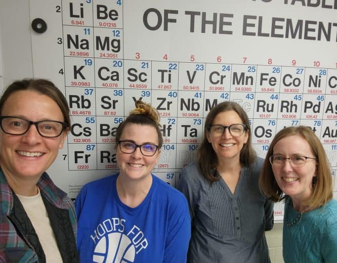 Science Teachers in front of the periodic table of elements.