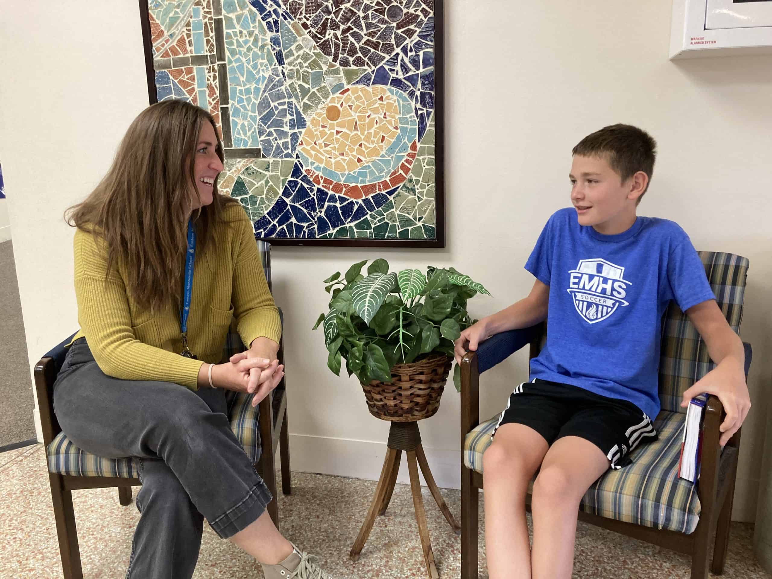 Ms. Cook and Anthony talk in the hall.